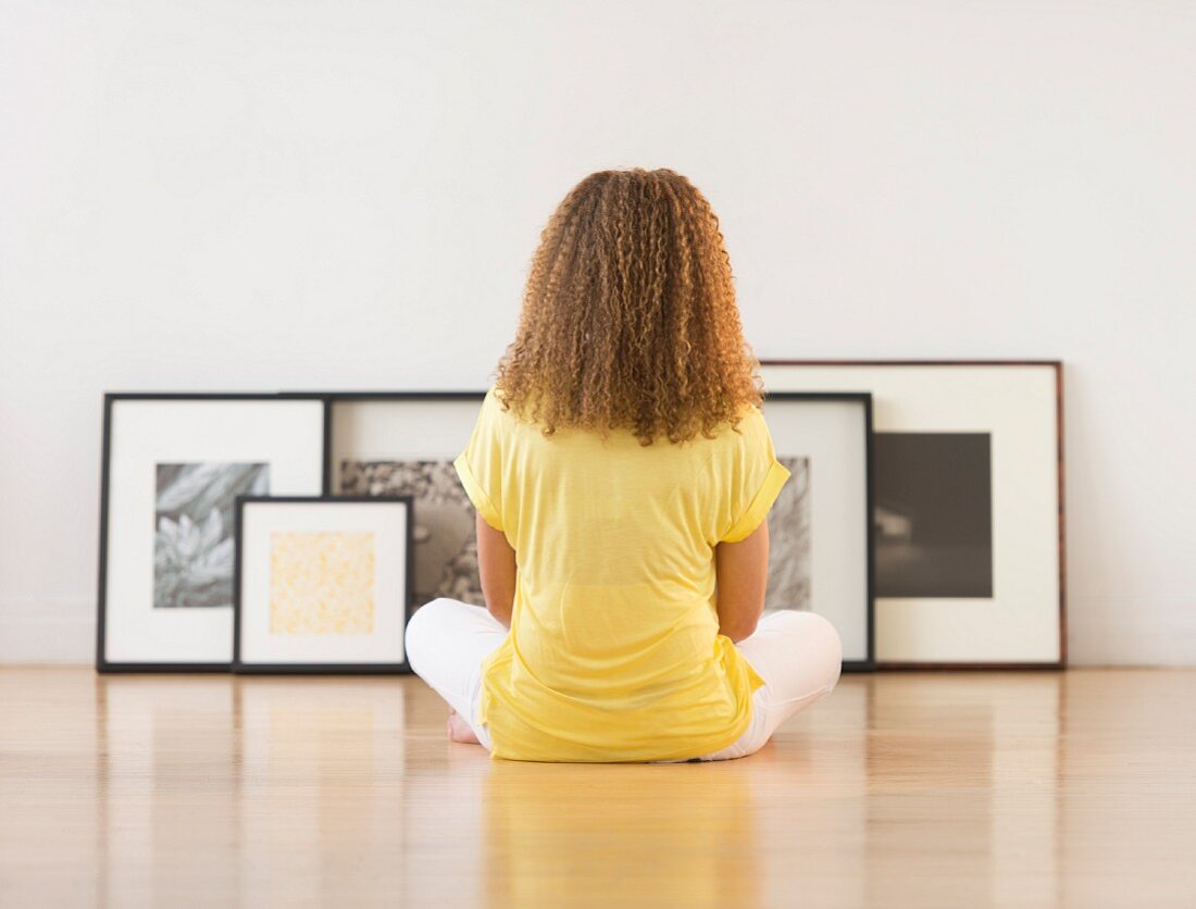 Woman sitting on floor looking at artworks