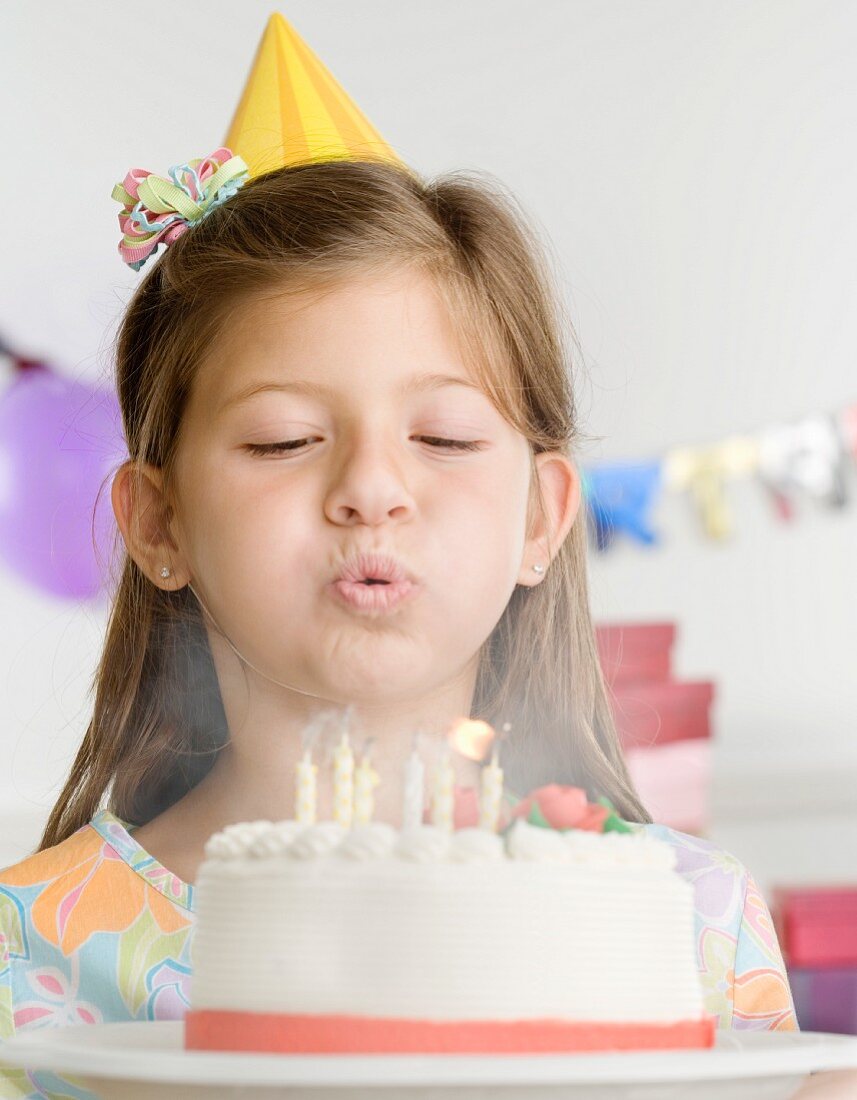 Mädchen bläst Kerzen auf der Geburtstagstorte aus