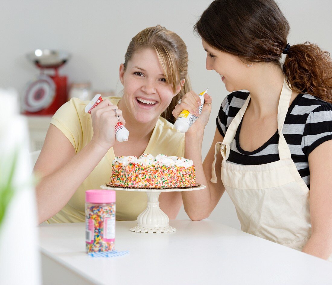 Zwei Teenager-Mädchen verzieren einen Kuchen
