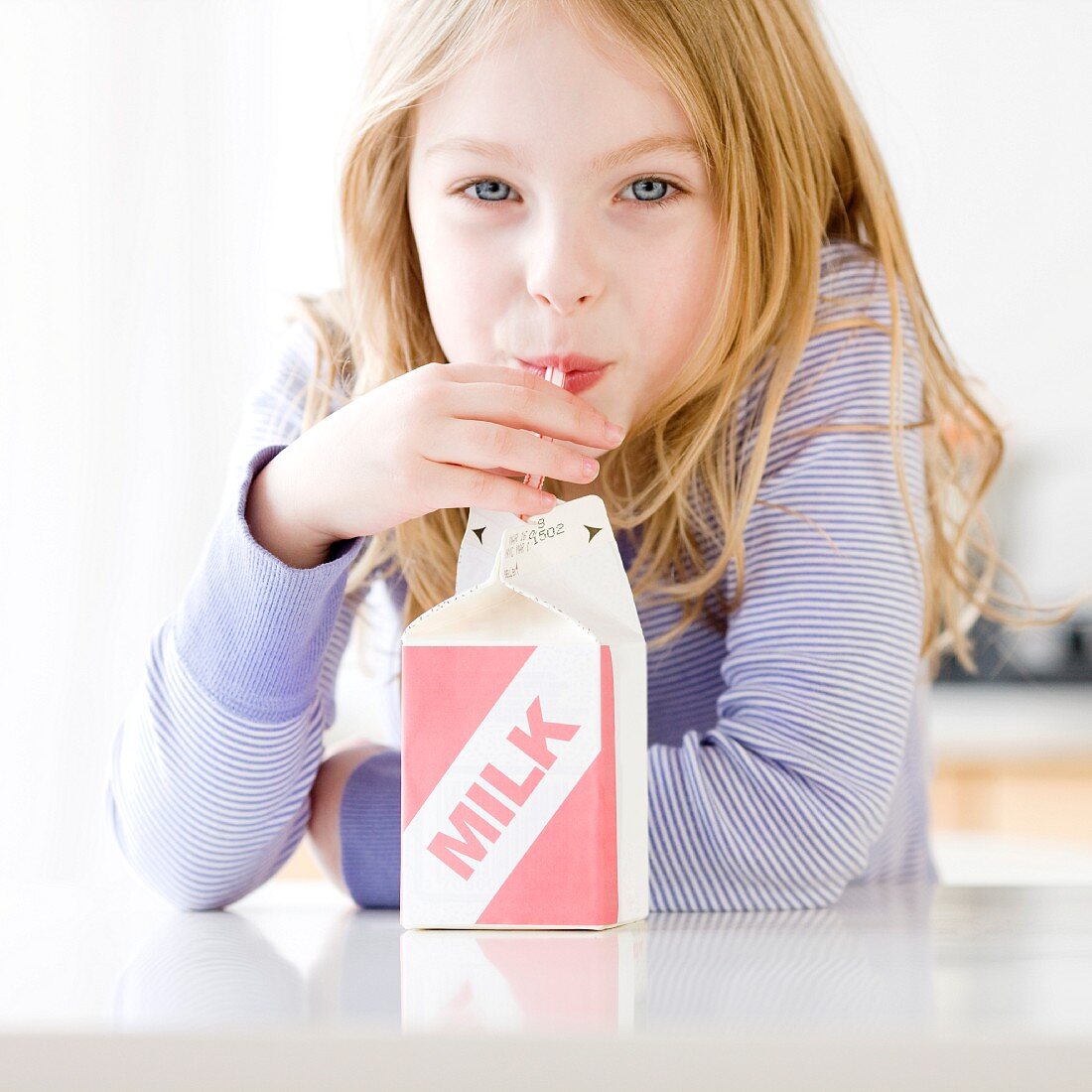 Mädchen trinkt Milch mit Strohhalm aus der Tüte