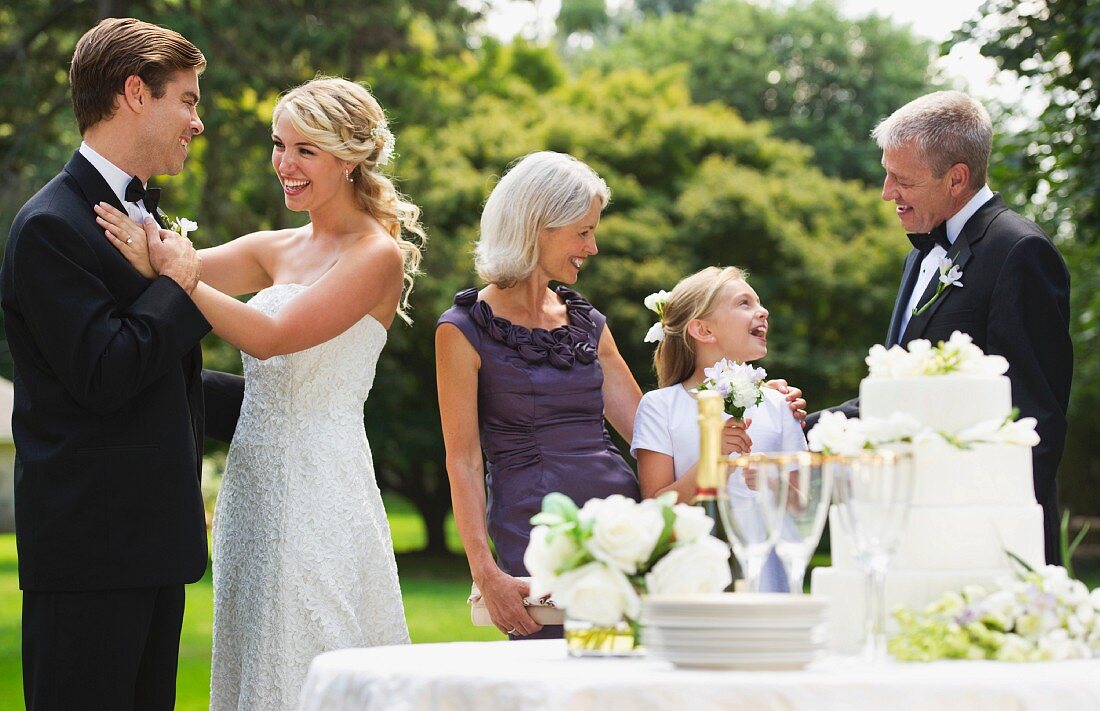 Fröhliche Hochzeitsgesellschaft mit Hochzeitstorte im Garten