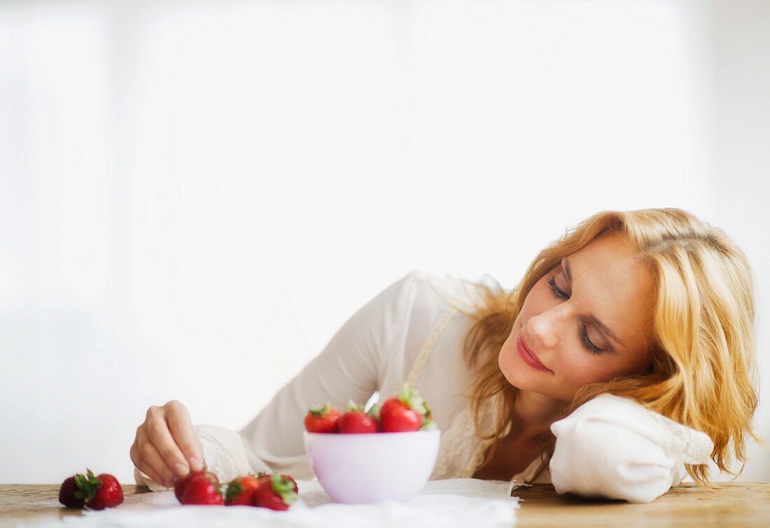Woman eating strawberries, studio shot