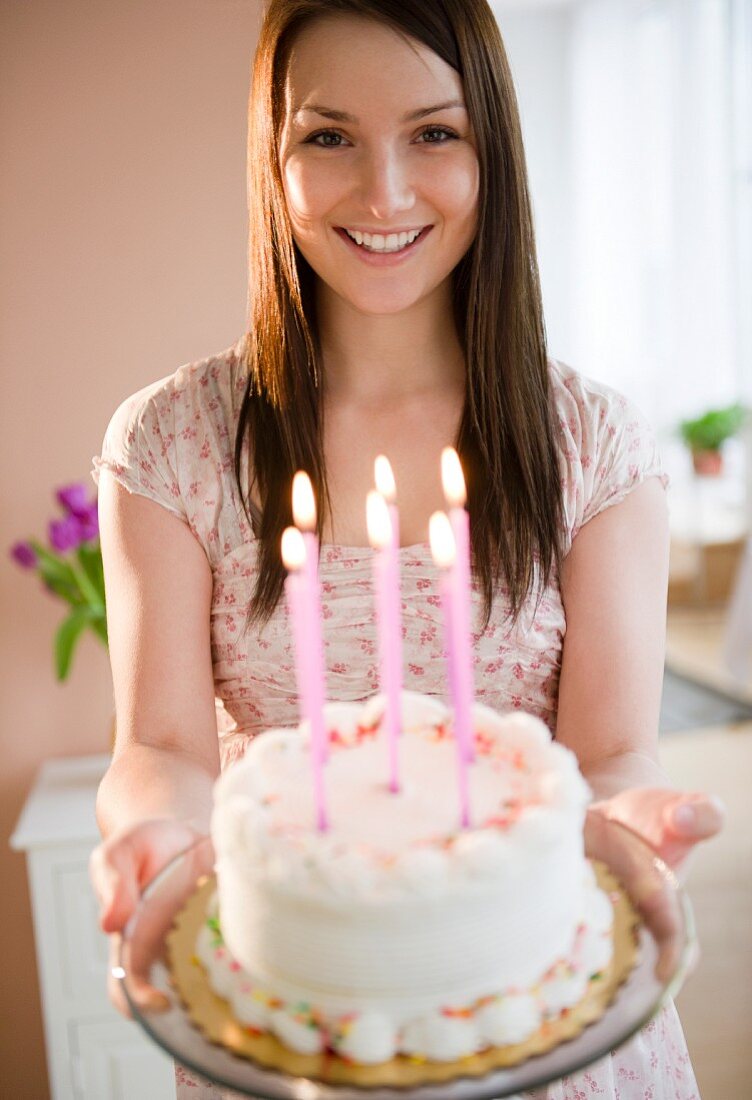 Junge Frau hält Geburtstagstorte mit Kerzen