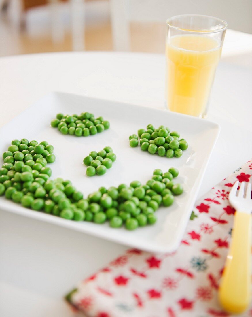 Close up of smiley on plate made of green peas