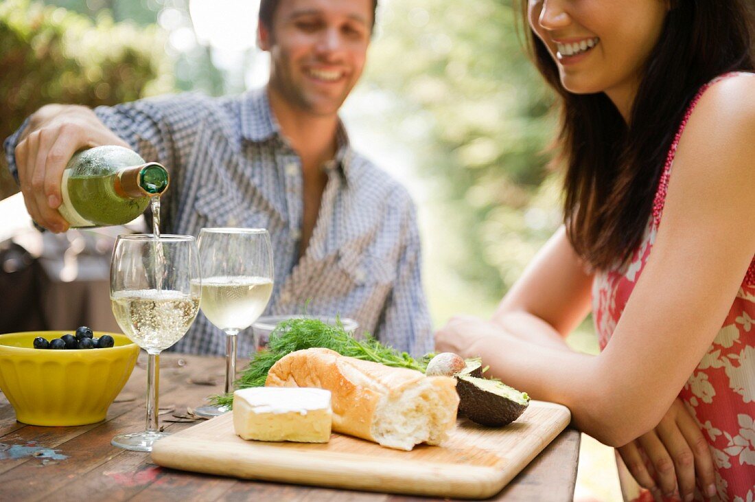 Junges Paar mit Brotzeit & Wein im Freien