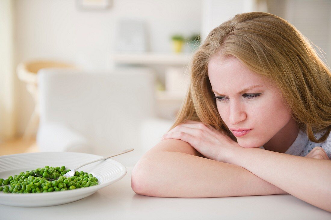 Woman leaning on table looking on green peas