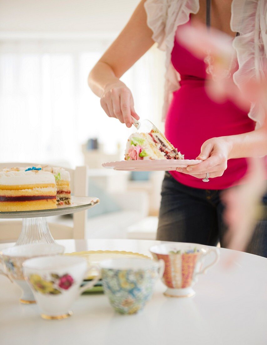 Schwangere Frau serviert Kuchen