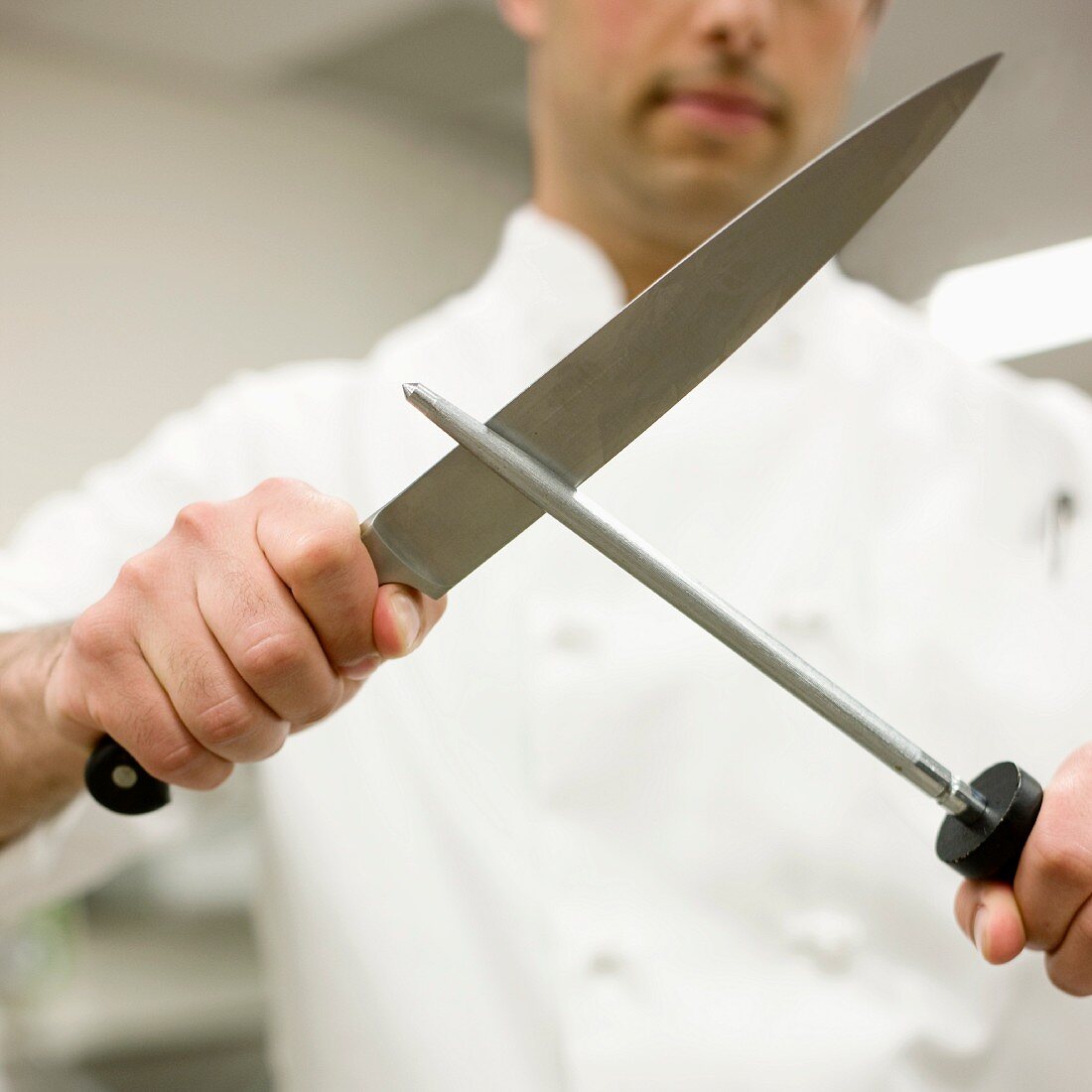 Chef sharpening knife in kitchen