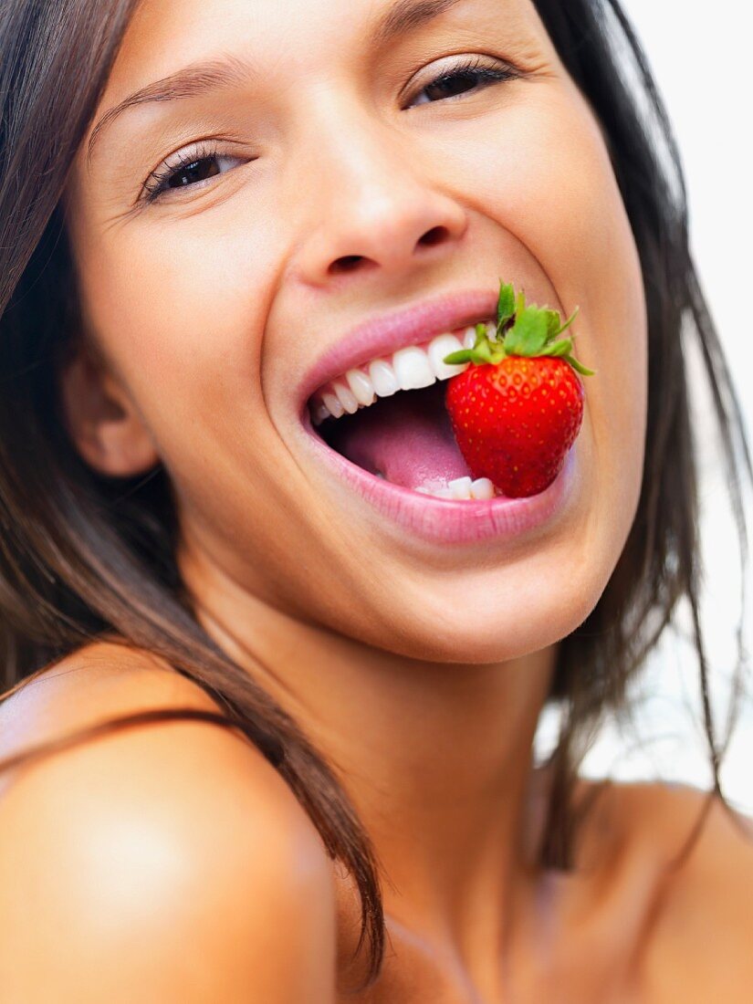 Junge Frau mit grosser Erdbeere im Mund