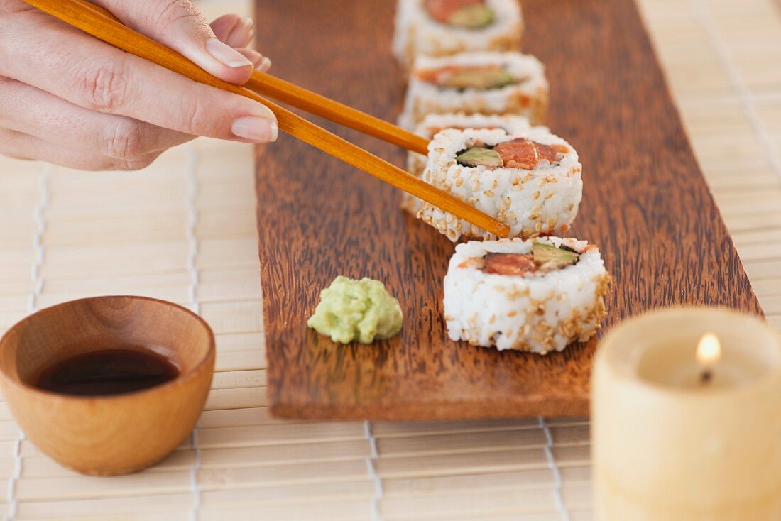 Woman holding sushi by chopsticks