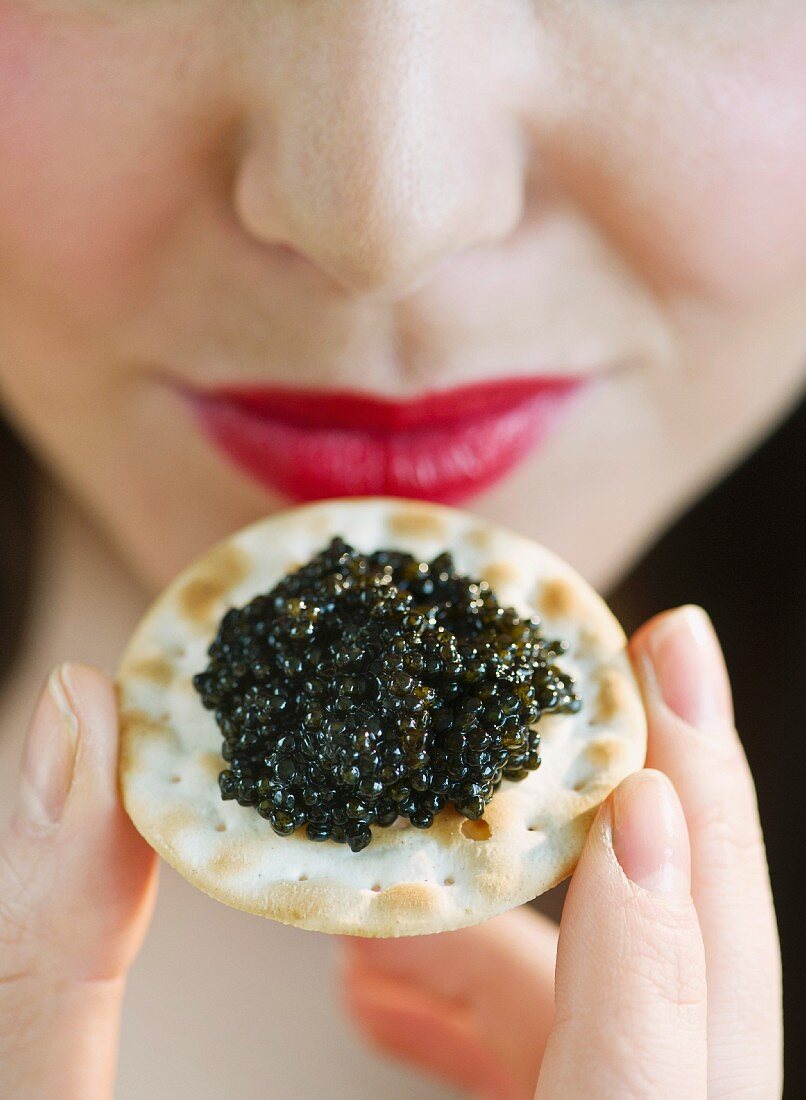 Young woman eating caviar snack, close-up of lips