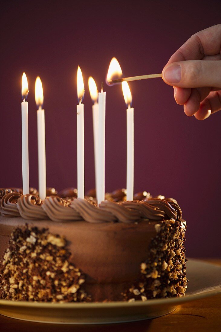 Studio shot of man igniting candles on chocolate birthday cake