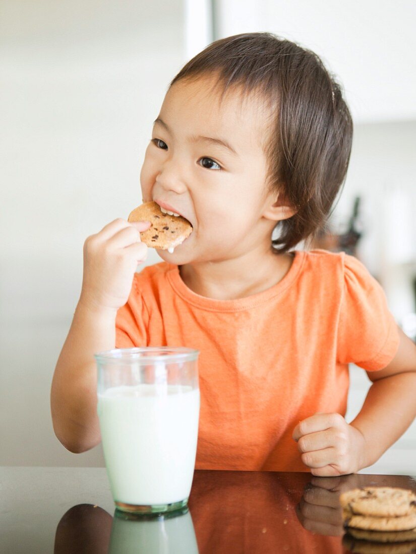 Mädchen isst Keks und trinkt Milch