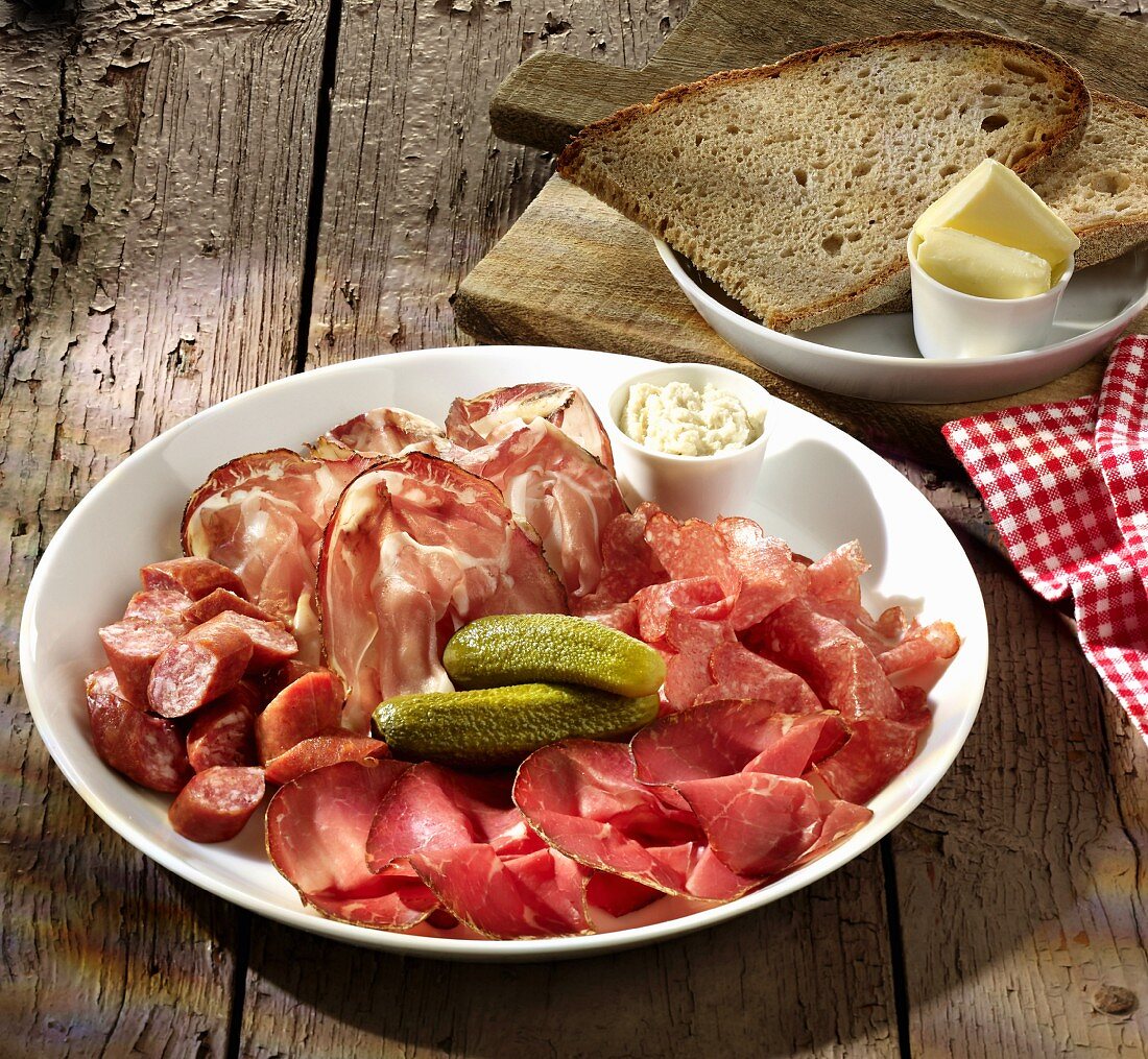 Sausage and ham platter with pickled gherkins, bread and butter