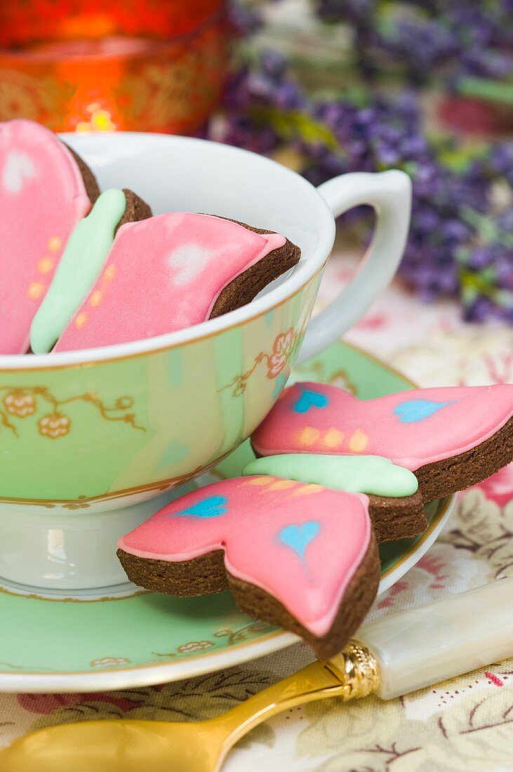 Schmetterlingskekse in einer Teetasse mit Untertasse, Teelicht, Lavendel