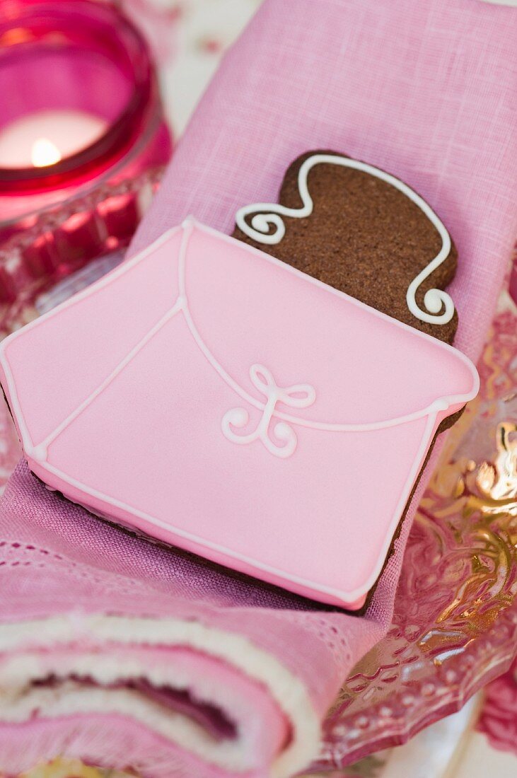 Handbag cookie on a pink cloth napkin in front of a tea light