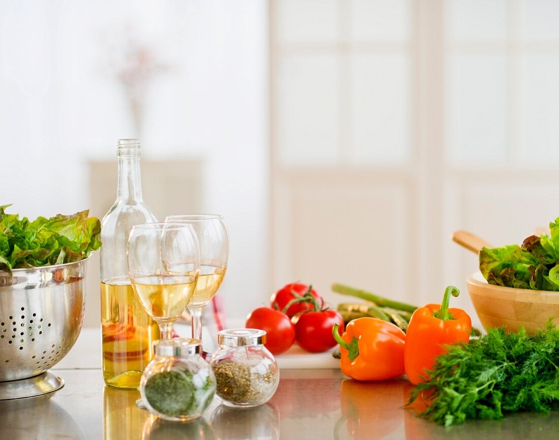 Nahaufnahme von Gemüse, Salat, Gewürzen und Wein in der Küche