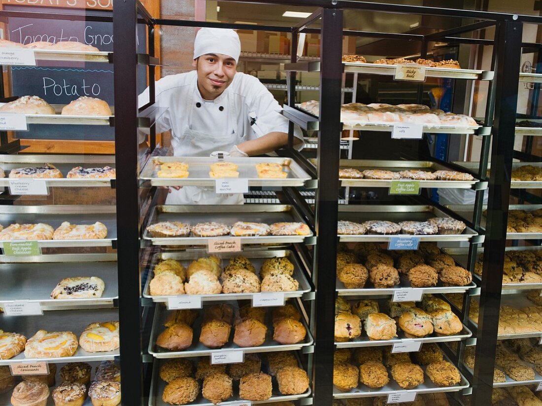 Baker standing behind trays of baked goods