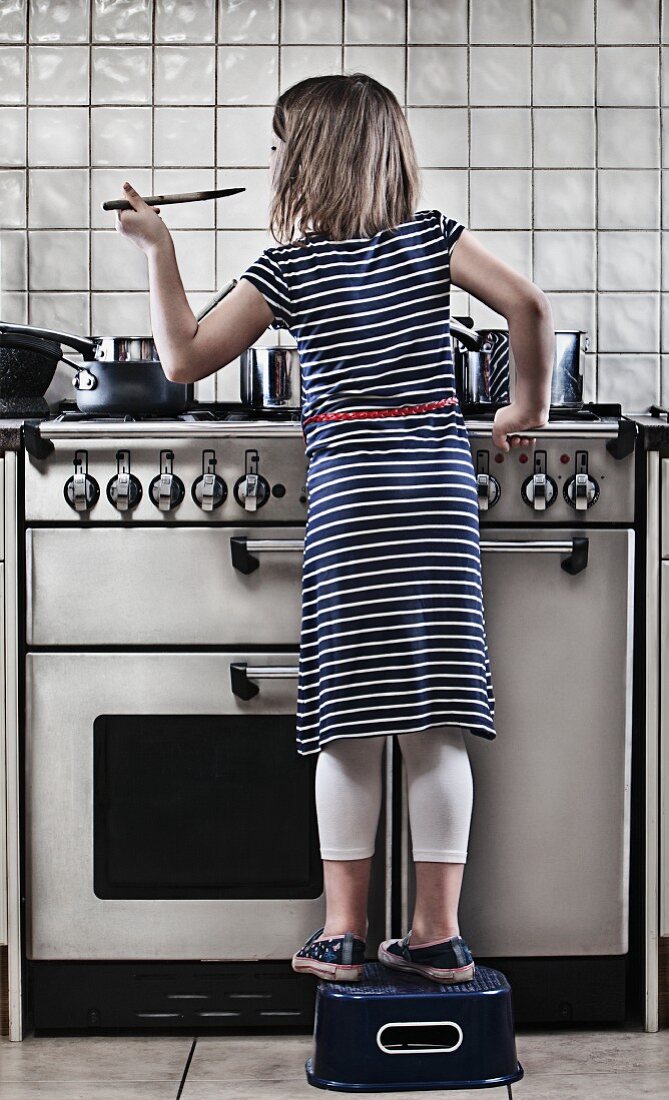 Girl (8-9) cooking in kitchen