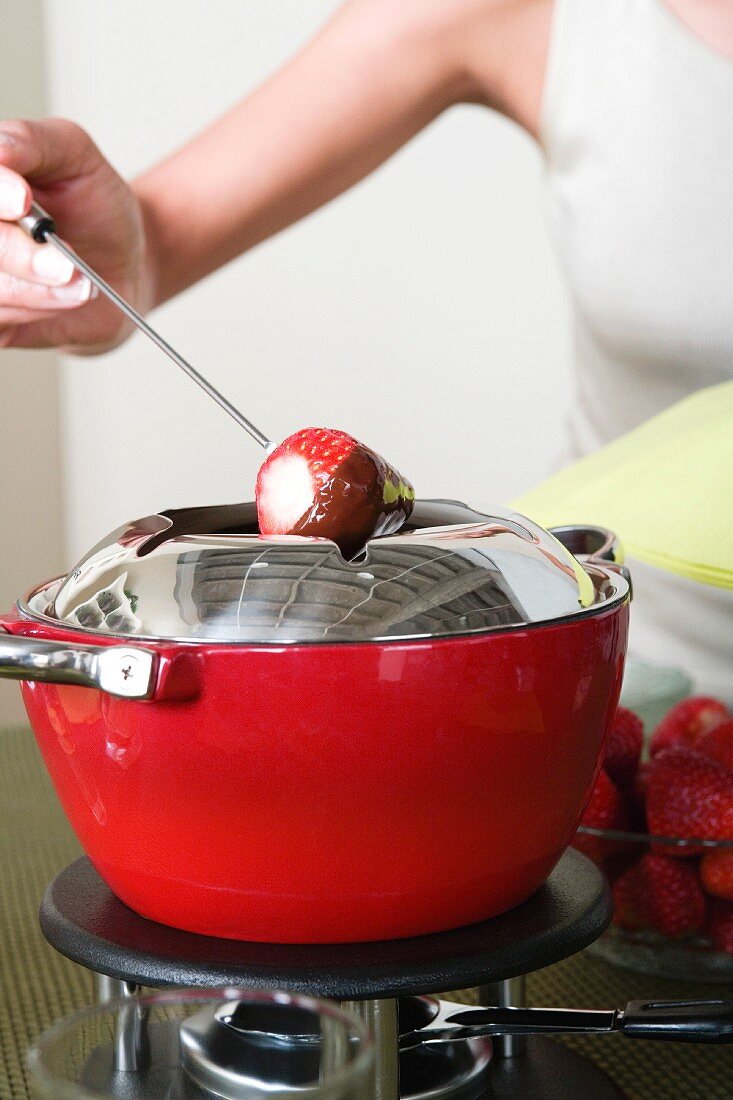 Woman dipping strawberries in chocolate mousse