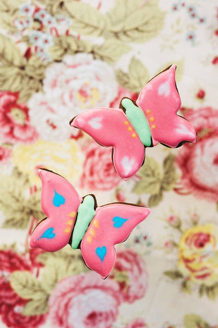 Two pink 'butterfly' cookies on a floral background