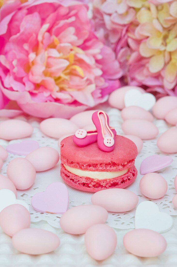 Pink macron decorated with home made 'pumps', surrounded by sugared almonds, sugar candies and peonies