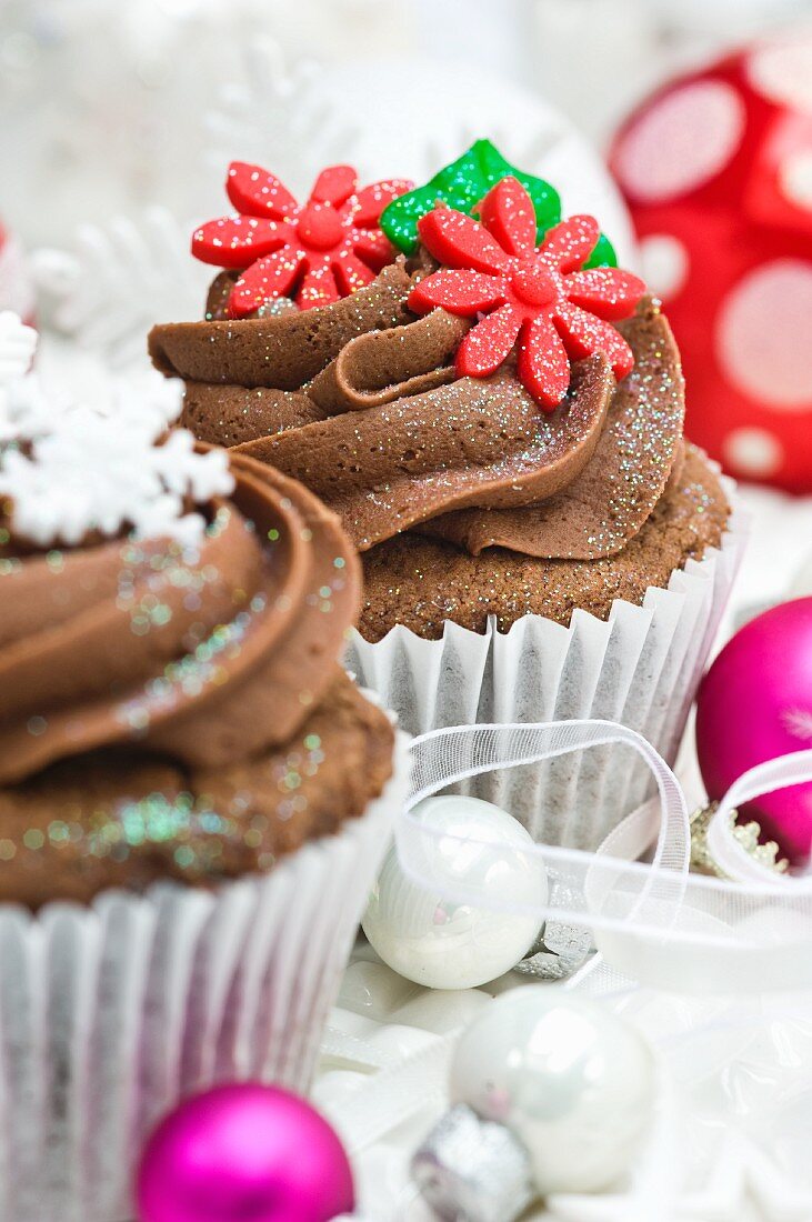 Schokoladencupcakes mit Zuckerblumen und Schneeflocken zu Weihnachten