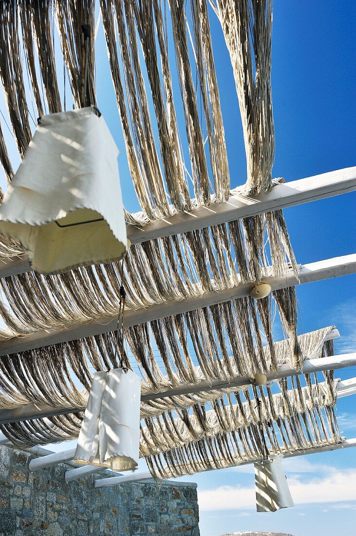 Pergola with woven rope roof and pendant lamps with white fabric lampshades