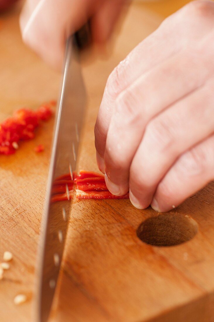 Thinly slicing red chili peppers