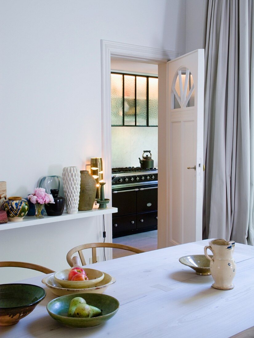 Wooden kitchen table and view through open door of vintage kitchen cooker