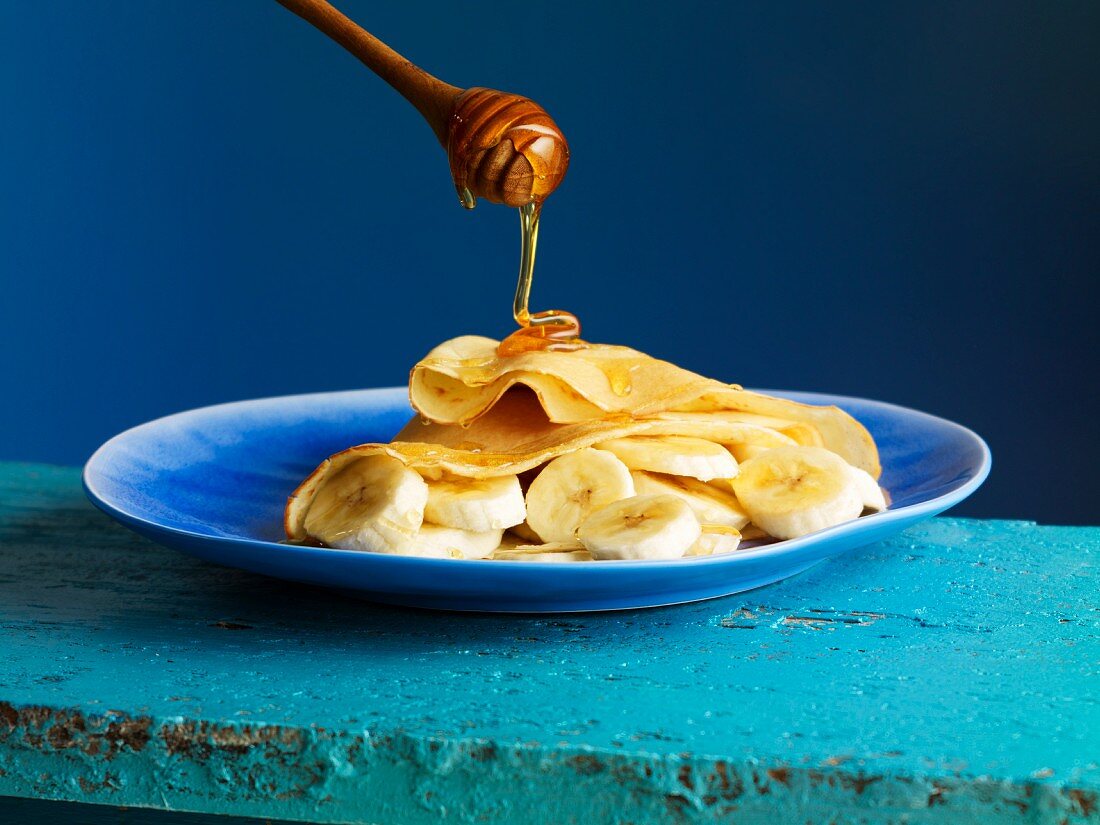 Honey flowing onto a crepe with banana slices