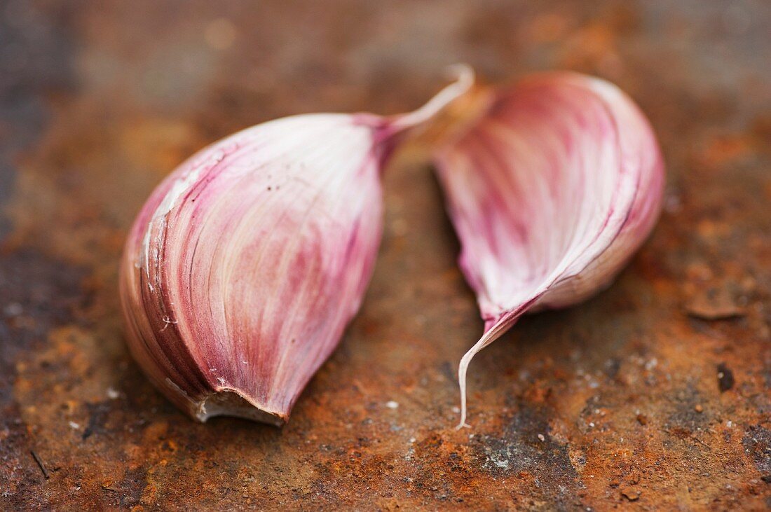 Two cloves of garlic (Allium sativum) on a rusty surface