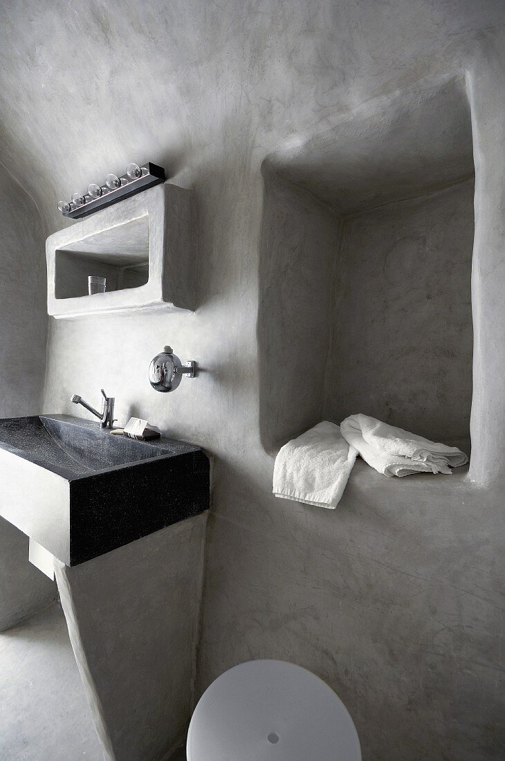 Stone washstand and niche in pale grey, limewashed wall in minimalist bathroom