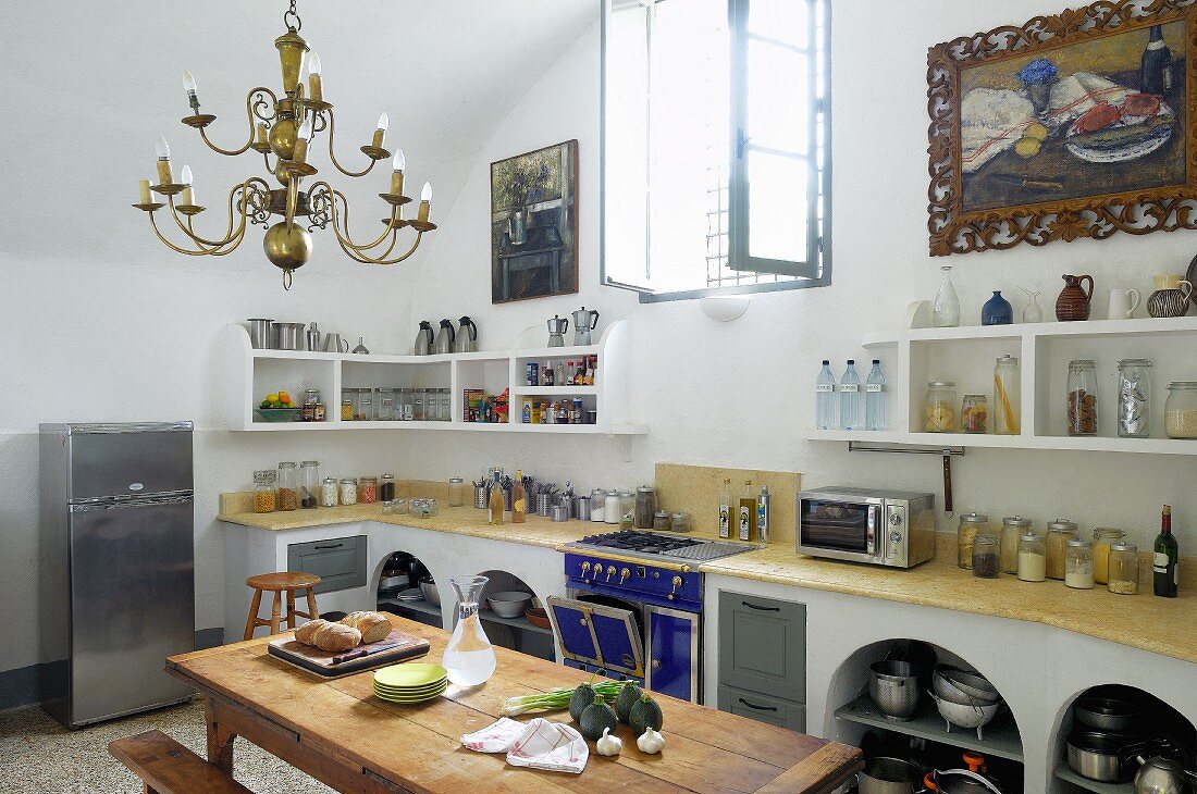 Converted former monastery with barrel vaulted ceiling and masonry kitchen counter; large still-life oil paintings above kitchen shelves