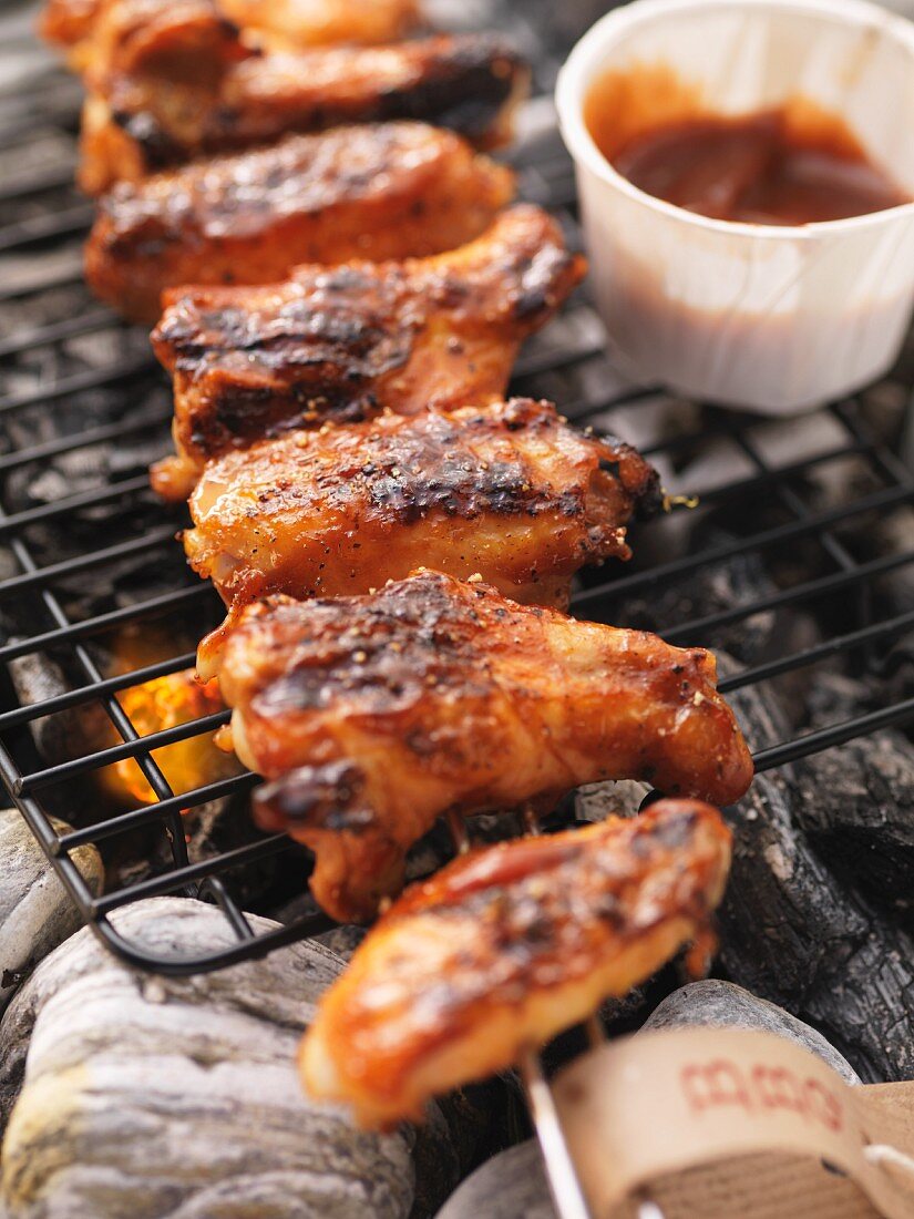 Barbecued chicken wings and barbecue sauce on the barbecue