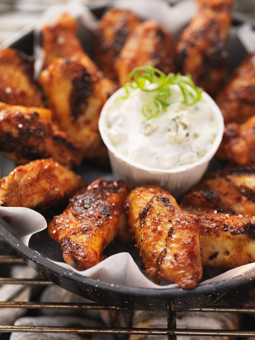 Gegrillte Hähnchenflügel mit Dip in einer Schale auf Grillrost