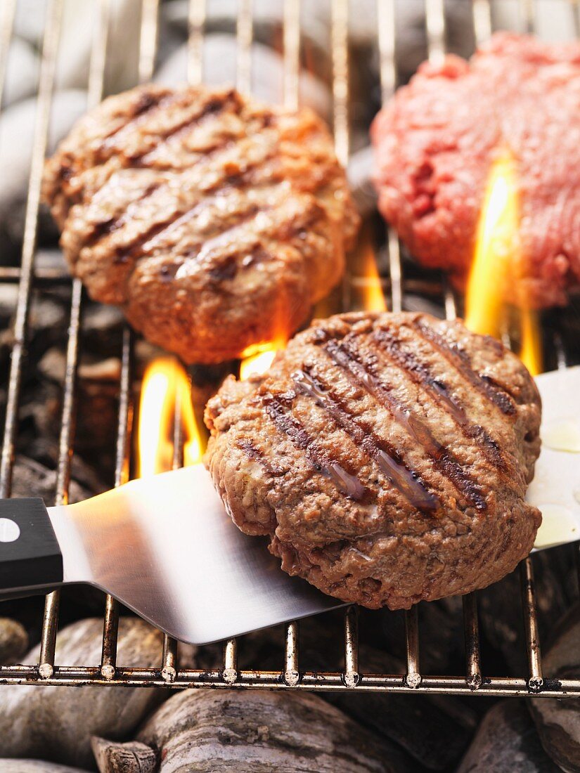 Beefburgers on the barbecue (raw and cooked)