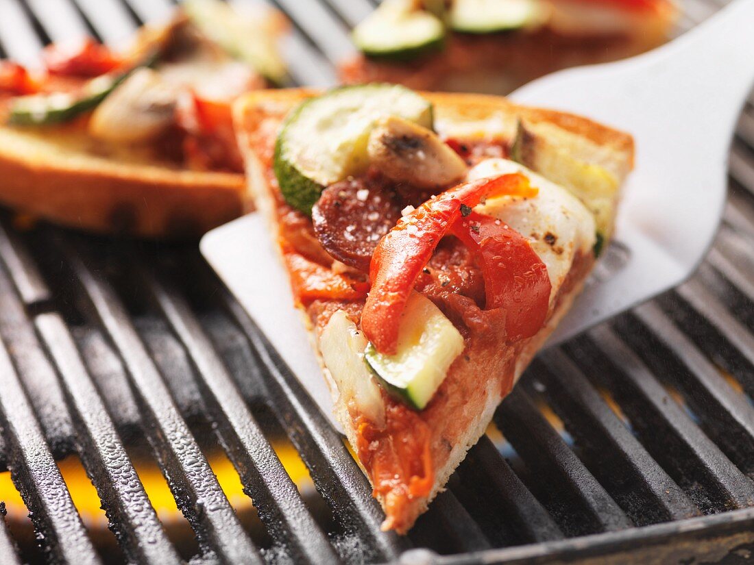 A slice of pizza, cooked on the barbecue, on a spatula
