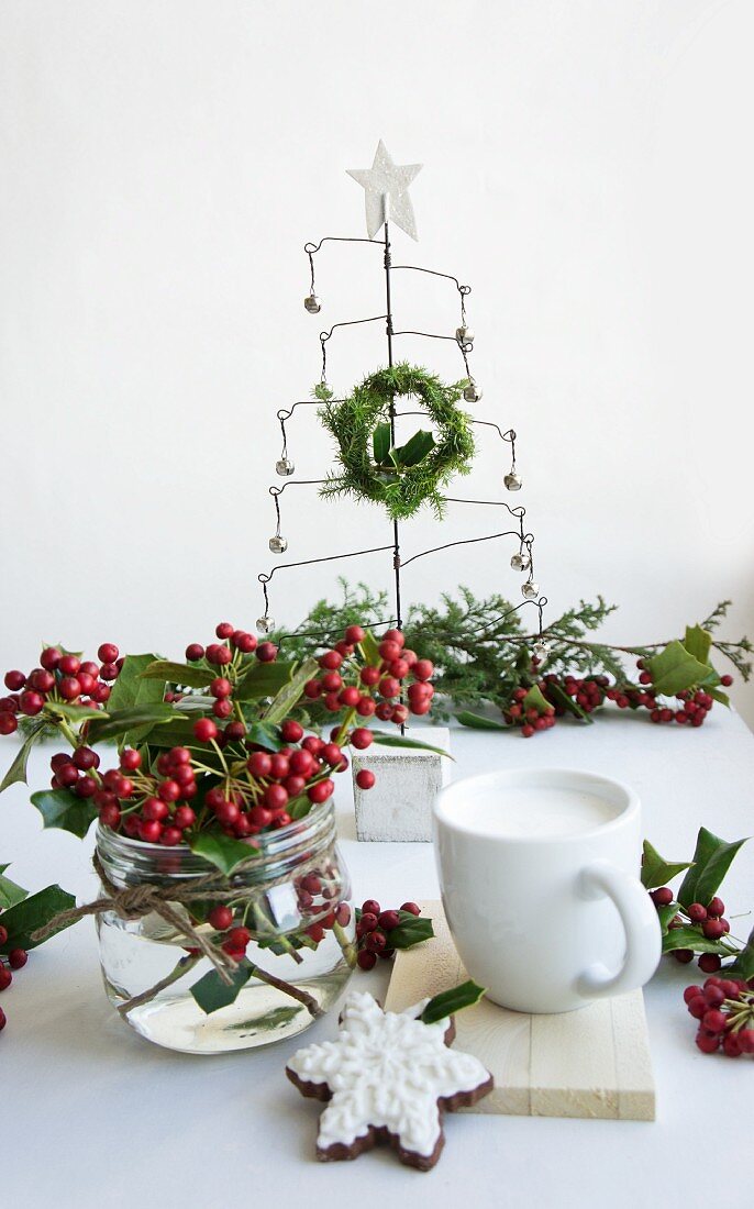 Tisch mit Strauß aus Ilexbeeren, Tannenbaum aus Draht und Gedeck mit Plätzchen