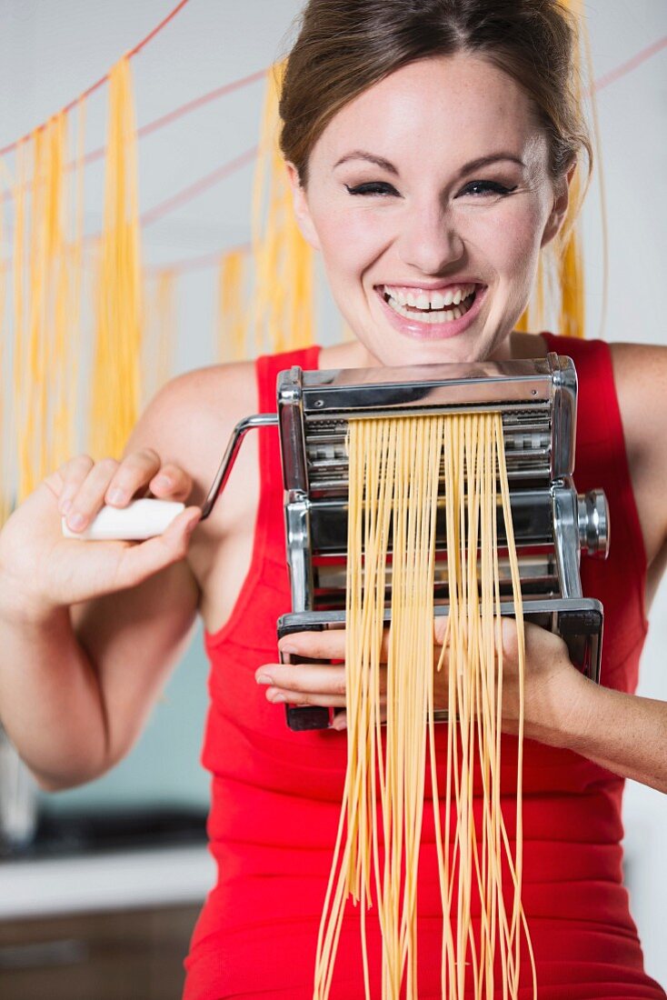 Germany, Young woman making pasta with machine