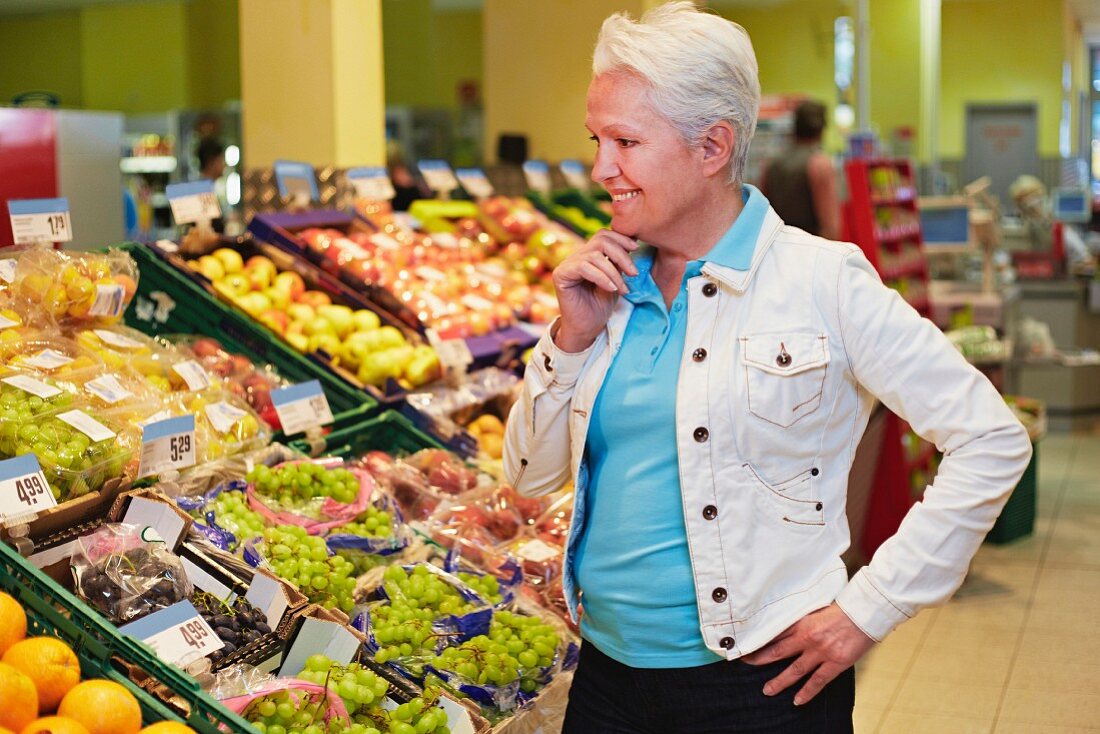 Ältere Frau überlegt im Supermarkt