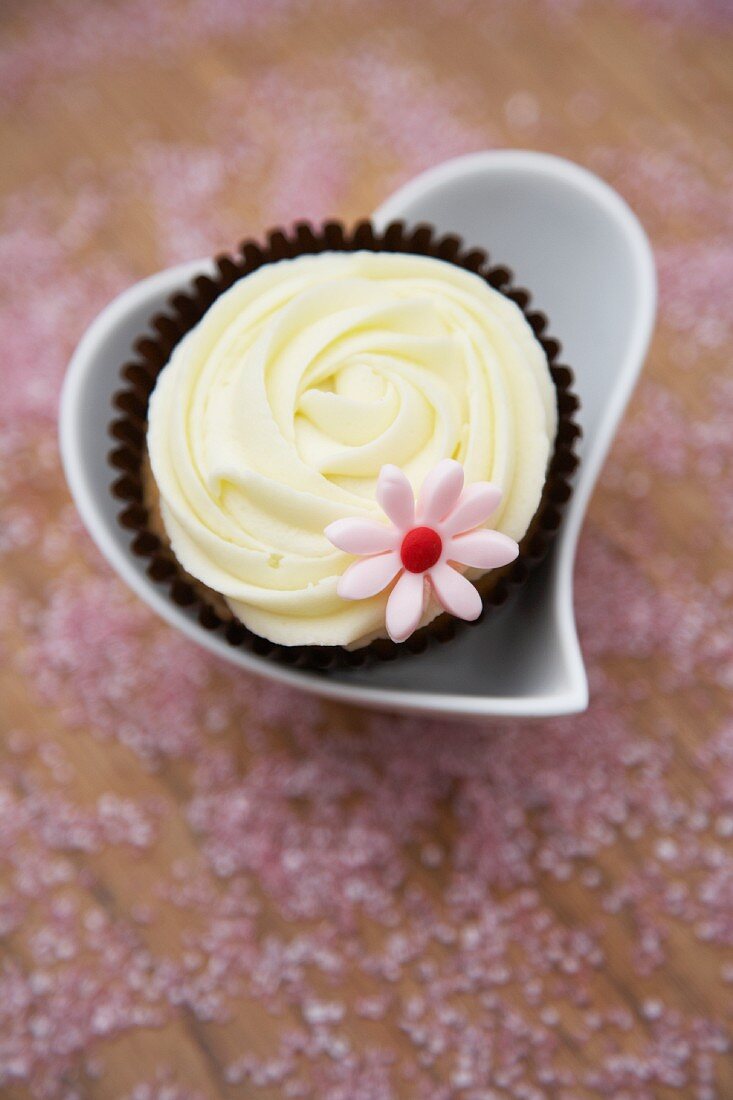 Weisser Schokoladen-Cupcake in herzförmigem Schälchen