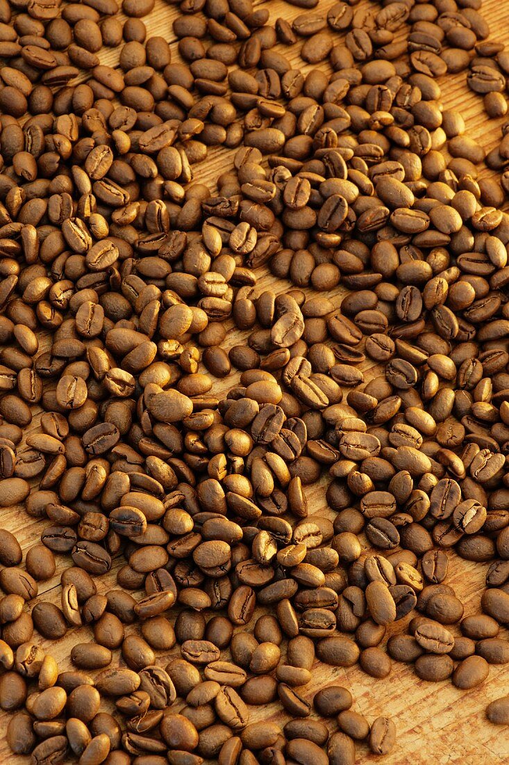 Lots of coffee beans on a wooden surface