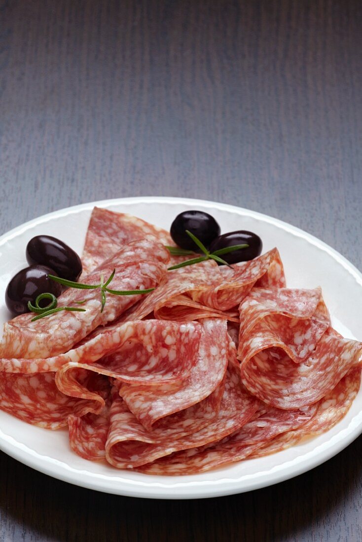 Slices of salami with olives on a plate
