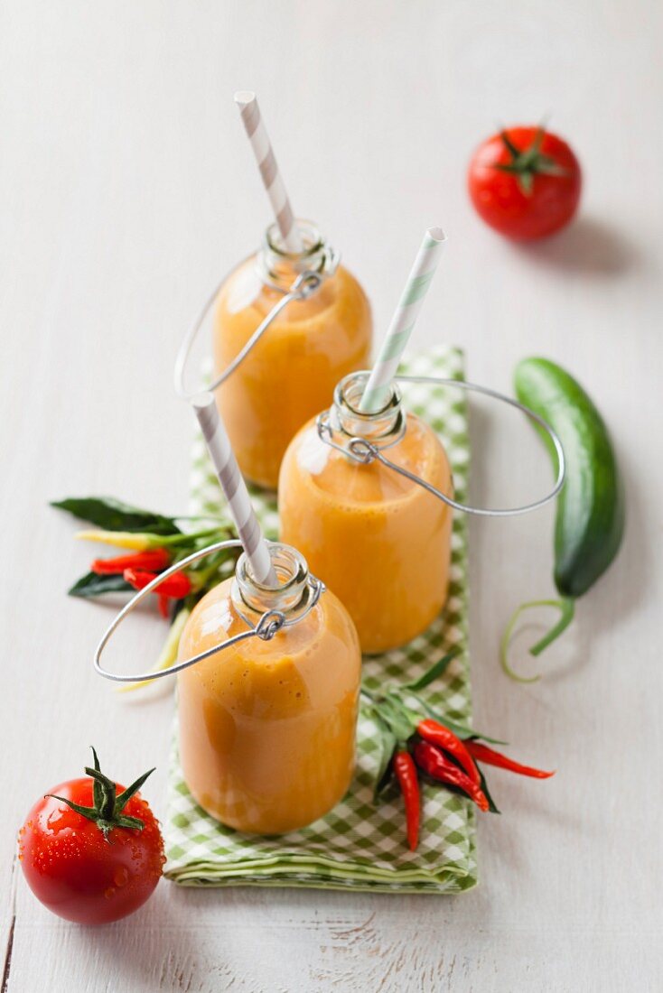 Bottles of gazpacho with chillies and tomatoes on napkin