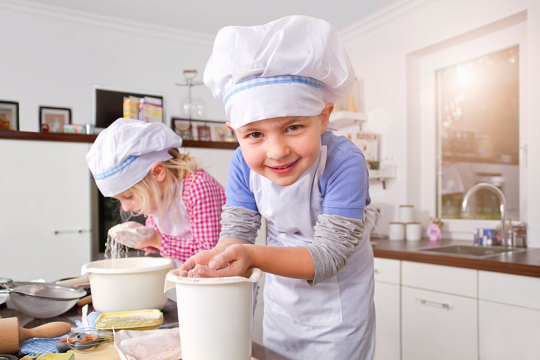Germany, Girl and boy making dough in kitchen