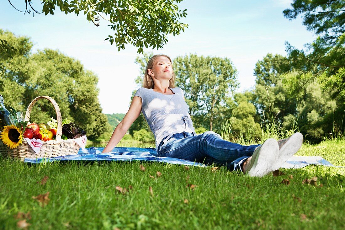 Germany, Cologne, Young woman relaxing at picnic