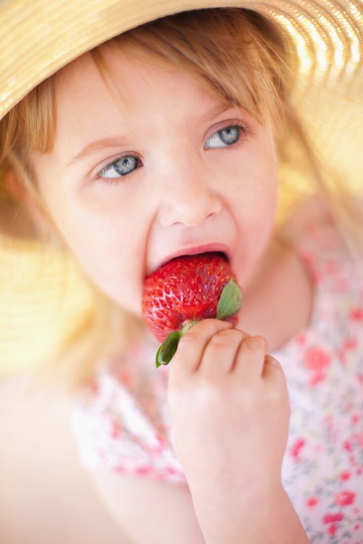 A girl eating a strawberry