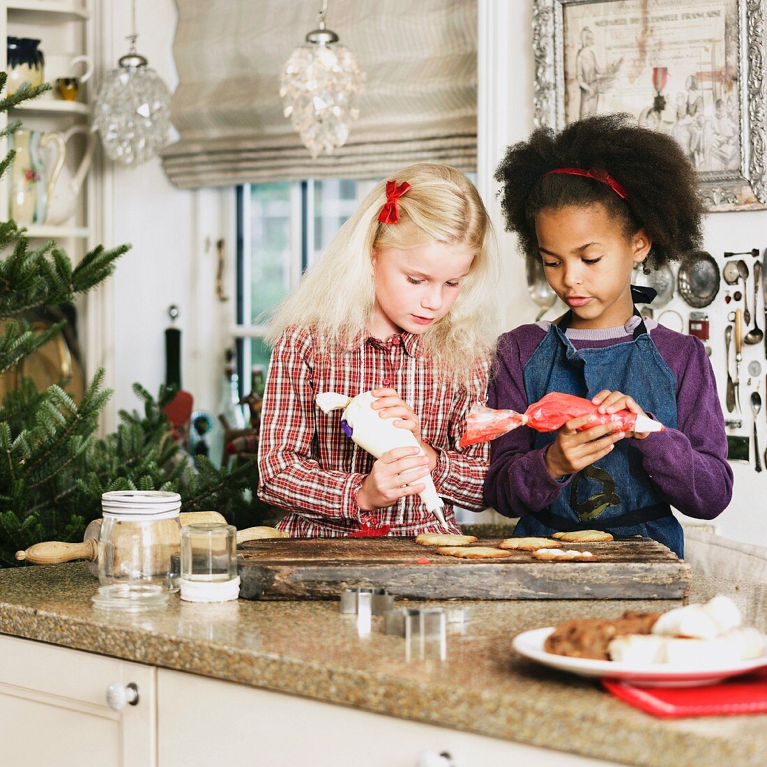 Two girls decorating Christmas biscuits