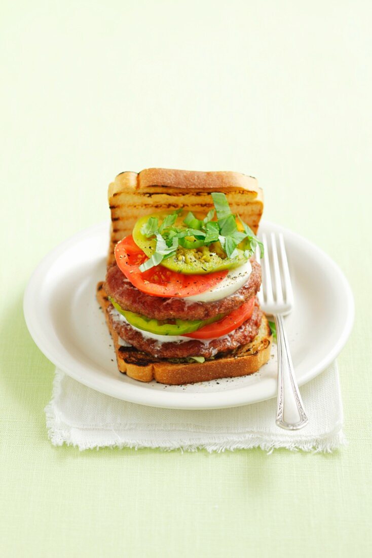 A burger topped with mozzarella, tomatoes and pesto (Italy)